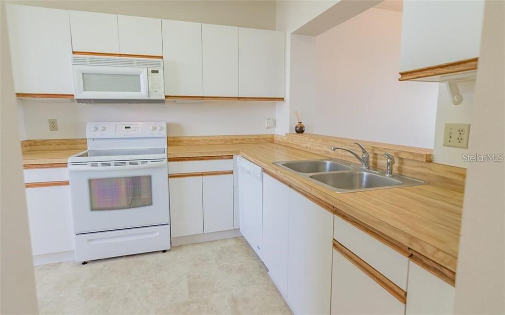 A kitchen features white cabinets, a white stove, a double sink, and light wood countertops — 7902 SAILBOAT KEY BOULEVARD S UNIT 402, SOUTH PASADENA, FL