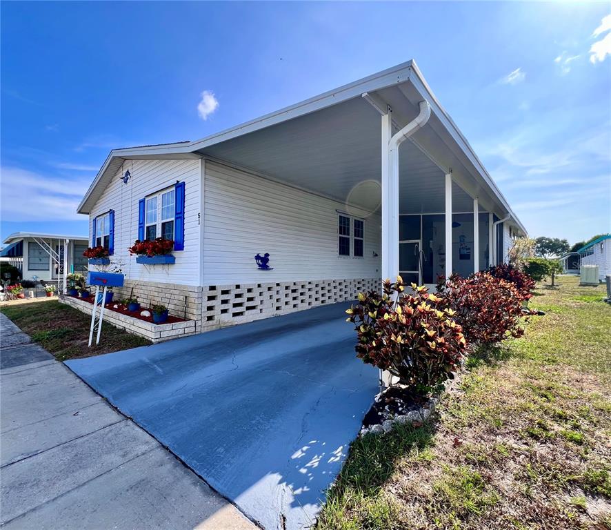 A white mobile home features a blue-painted driveway, a carport, and blue window shutters — 51 PINDO PALM STREET E, LARGO, FL