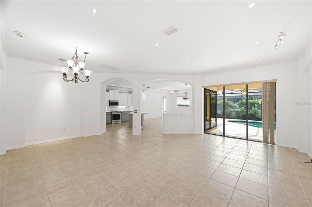 A spacious living area with tile floors, arched entryways, and sliding glass doors to a pool — 6611 CHICKADEE LANE, BRADENTON, FL