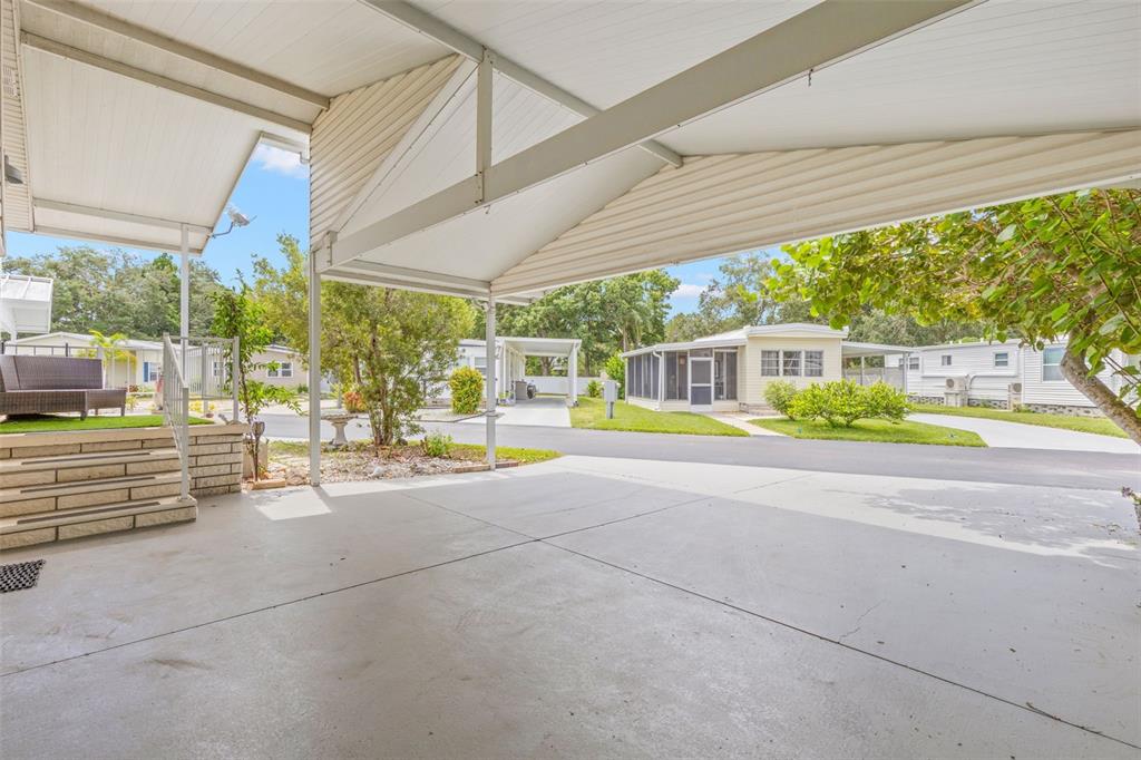 A concrete carport with a metal roof overlooks a residential street with neighboring mobile homes — 357 MOUNT SAXON AVENUE NE UNIT 323, ST PETERSBURG, FL