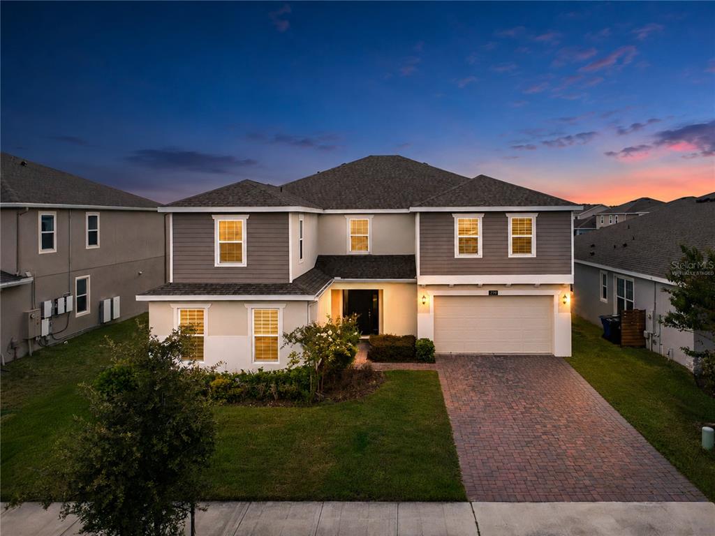 A two-story suburban house with a brick driveway and a two-car garage at dusk — 2737 NOTTEL DRIVE, ST CLOUD, FL