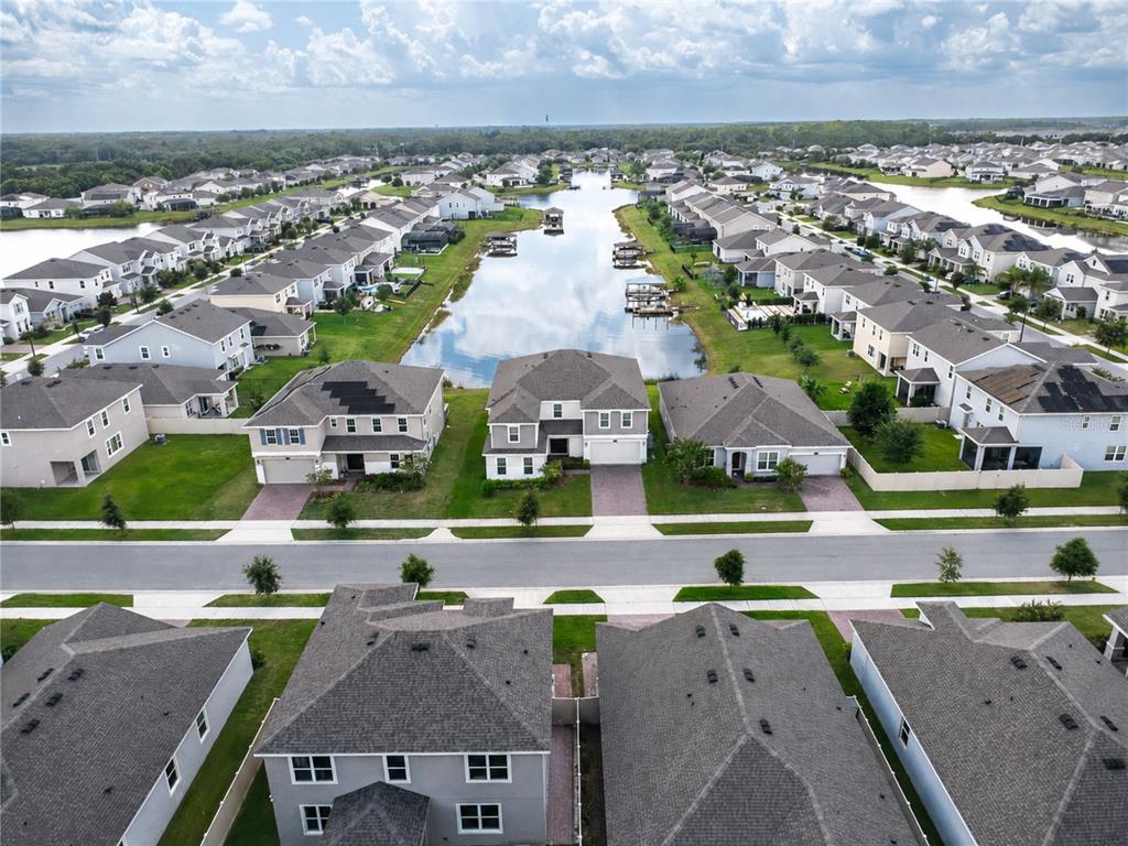 An aerial view shows a suburban neighborhood with houses surrounding a central lake — 2737 NOTTEL DRIVE, ST CLOUD, FL