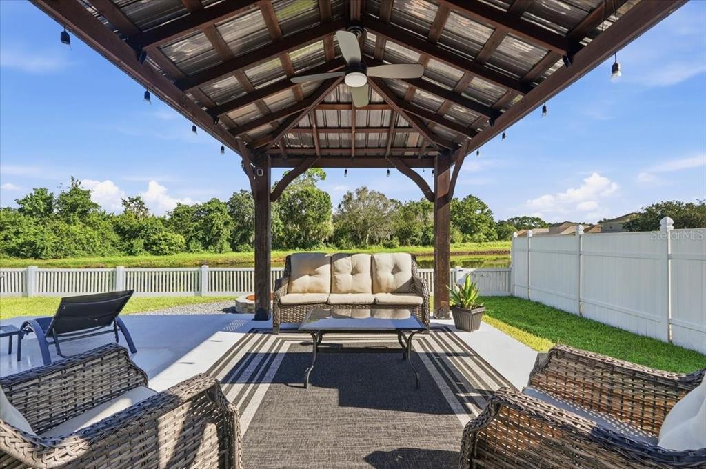 A covered patio features a wooden gazebo, outdoor furniture, and a view of a fenced yard — 3116 KEARNS ROAD, MULBERRY, FL