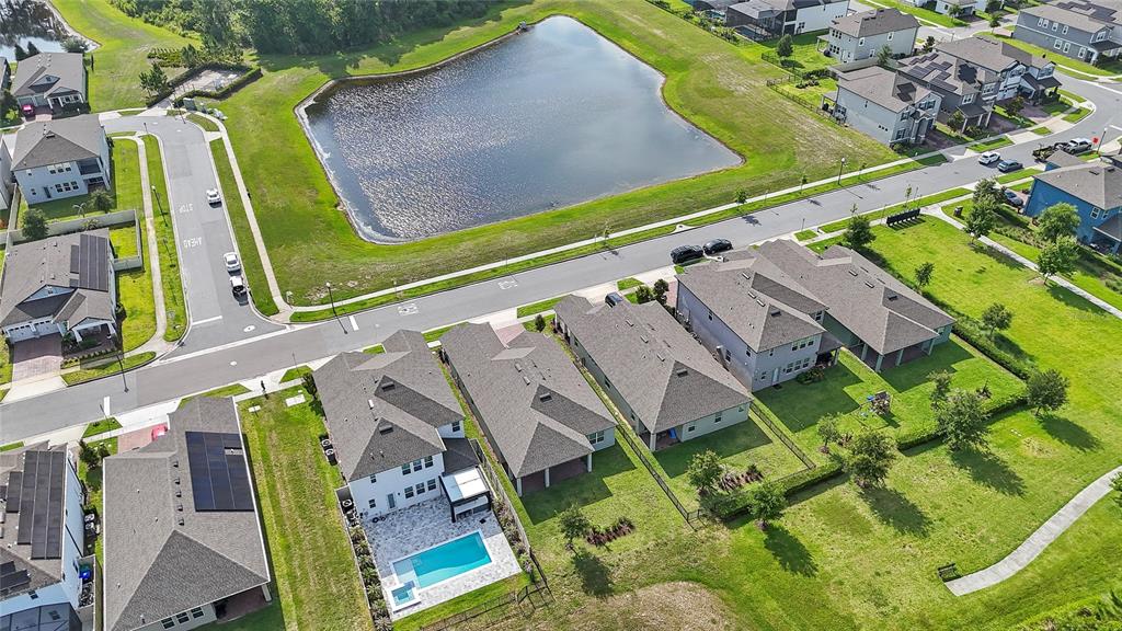 An exterior view of three suburban houses with gray siding, brick driveways, and manicured lawns — 12410 ENCORE AT OVATION WAY, WINTER GARDEN, FL