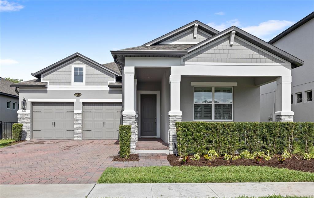 An aerial view shows three suburban houses with driveways and lawns near a pond — 12410 ENCORE AT OVATION WAY, WINTER GARDEN, FL