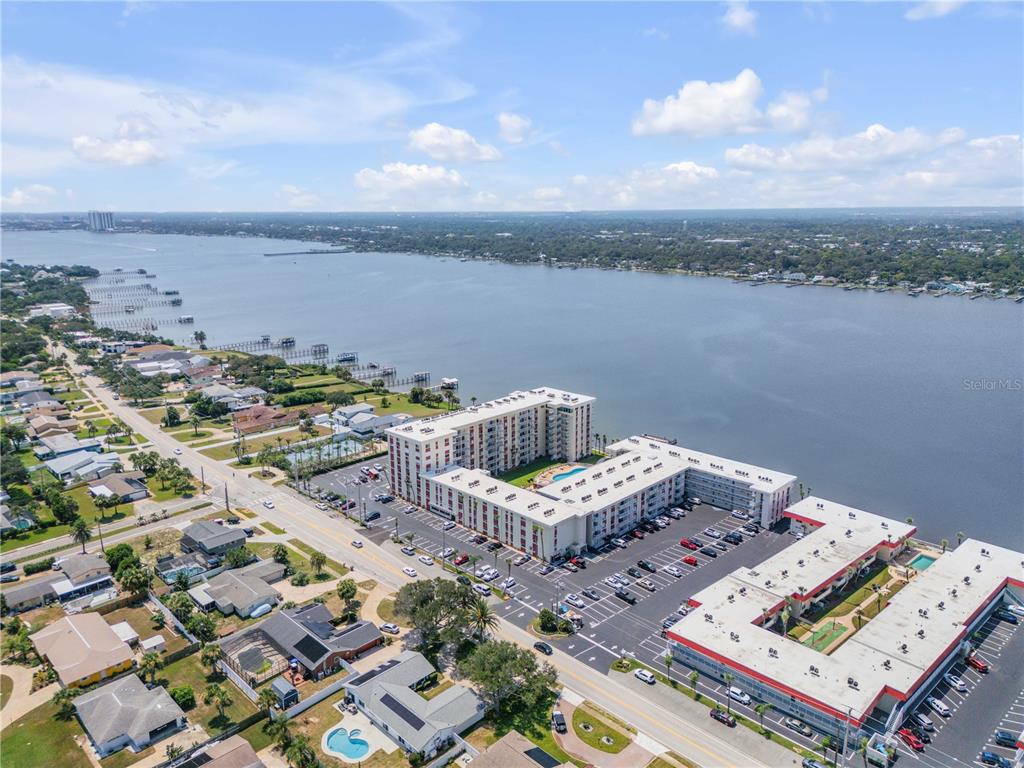An aerial view shows a large apartment complex situated along a wide river — 2711 N HALIFAX AVENUE UNIT 372, DAYTONA BEACH, FL