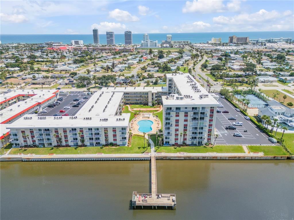 An aerial view shows a multi-story apartment complex with a pool, parking lot, and pier — 2711 N HALIFAX AVENUE UNIT 372, DAYTONA BEACH, FL