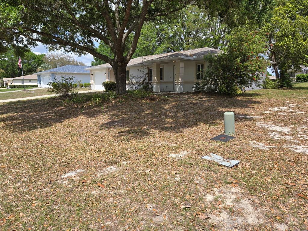A single-story house with a white exterior, a garage, and a large tree in front — 6121 SW 103RD LOOP, OCALA, FL