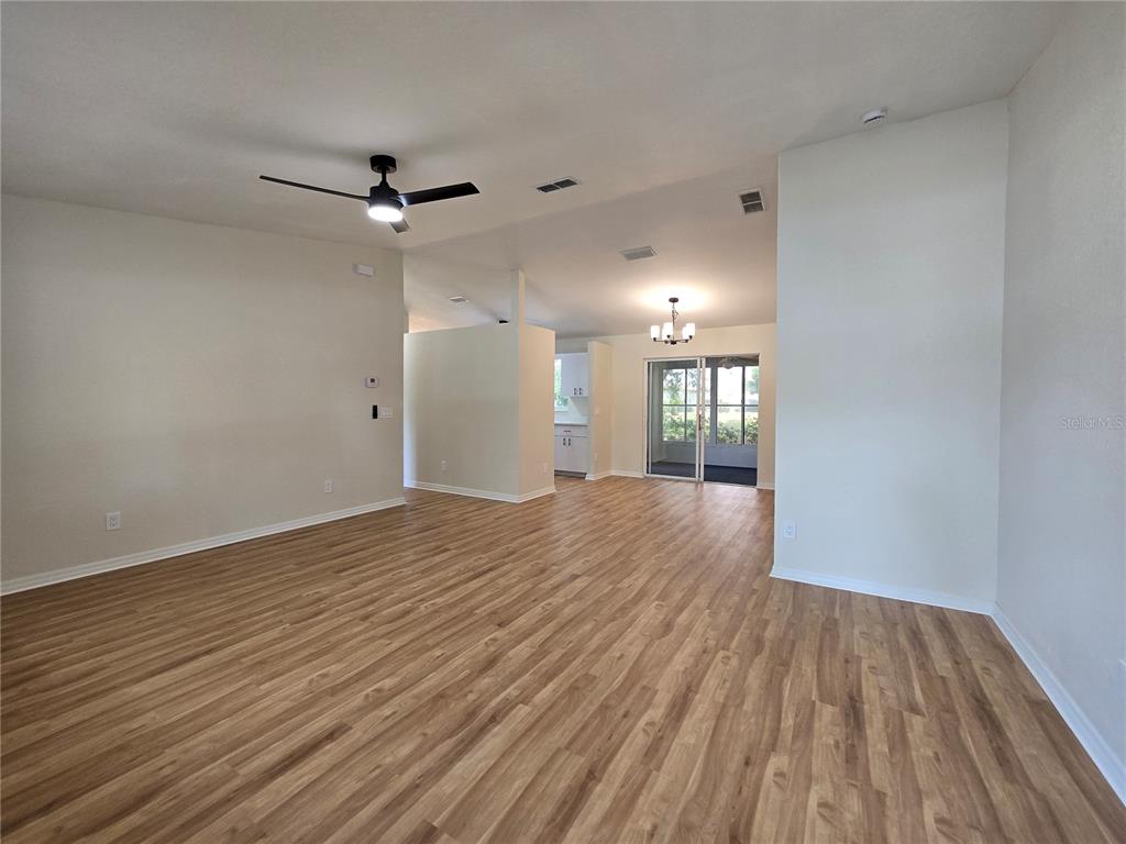 An open-concept living and dining area features light wood-look flooring and a ceiling fan — 6121 SW 103RD LOOP, OCALA, FL
