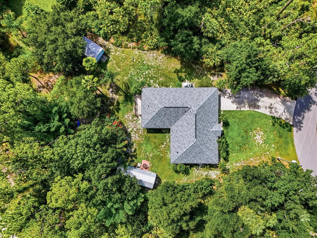 An aerial view shows a house with a gray roof surrounded by dense green trees — 3002 MONCRIEF AVE, NORTH PORT, FL