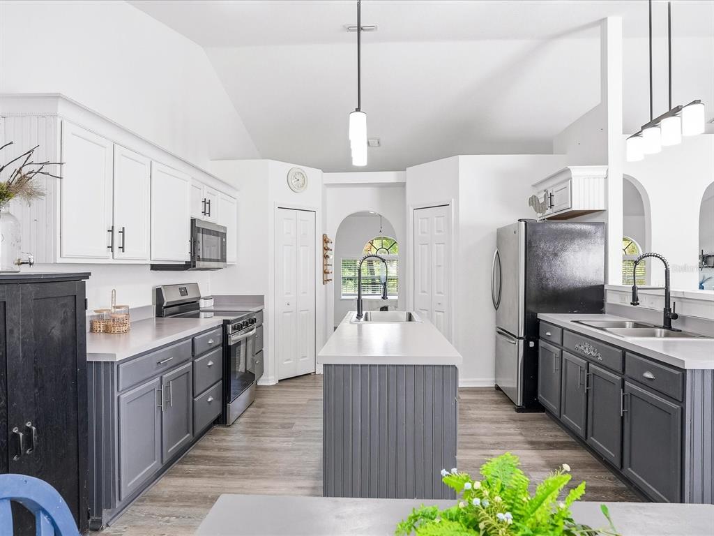 A kitchen features white upper cabinets, gray lower cabinets, a central island, and stainless appliances — 3002 MONCRIEF AVE, NORTH PORT, FL