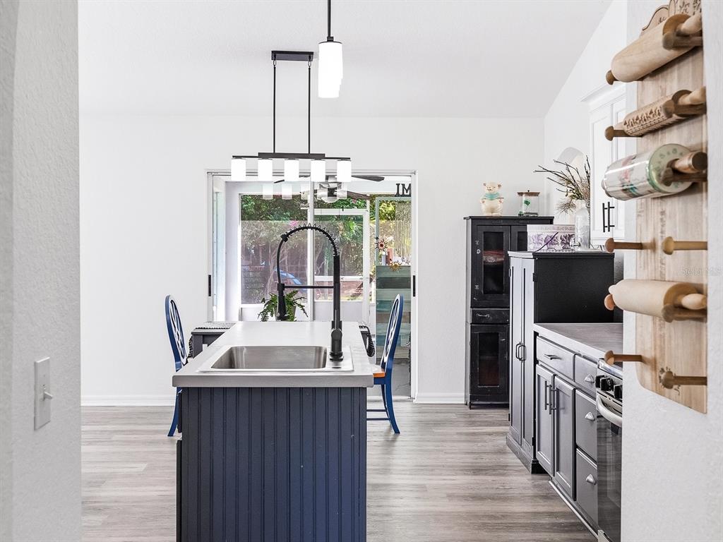 A kitchen features a blue island with a sink, grey cabinets, and a rolling pin rack — 3002 MONCRIEF AVE, NORTH PORT, FL