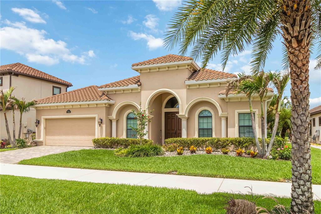 A single-story stucco house with a tile roof, arched windows, and a two-car garage — 7966 WYNDHAM DRIVE, MELBOURNE, FL
