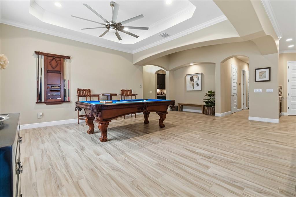 A game room features a pool table, wood-look tile flooring, and a tray ceiling — 7966 WYNDHAM DRIVE, MELBOURNE, FL