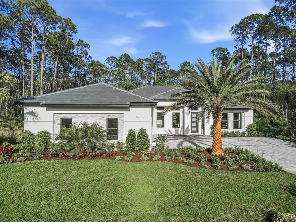 A modern single-story house with a white exterior, stone accents, and a paved driveway — 461 N TYMBER CREEK ROAD, ORMOND BEACH, FL