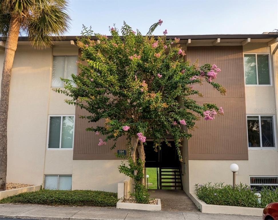 A multi-story apartment building exterior features a flowering crape myrtle tree in front — 554 ORANGE DRIVE UNIT 15, ALTAMONTE SPRINGS, FL