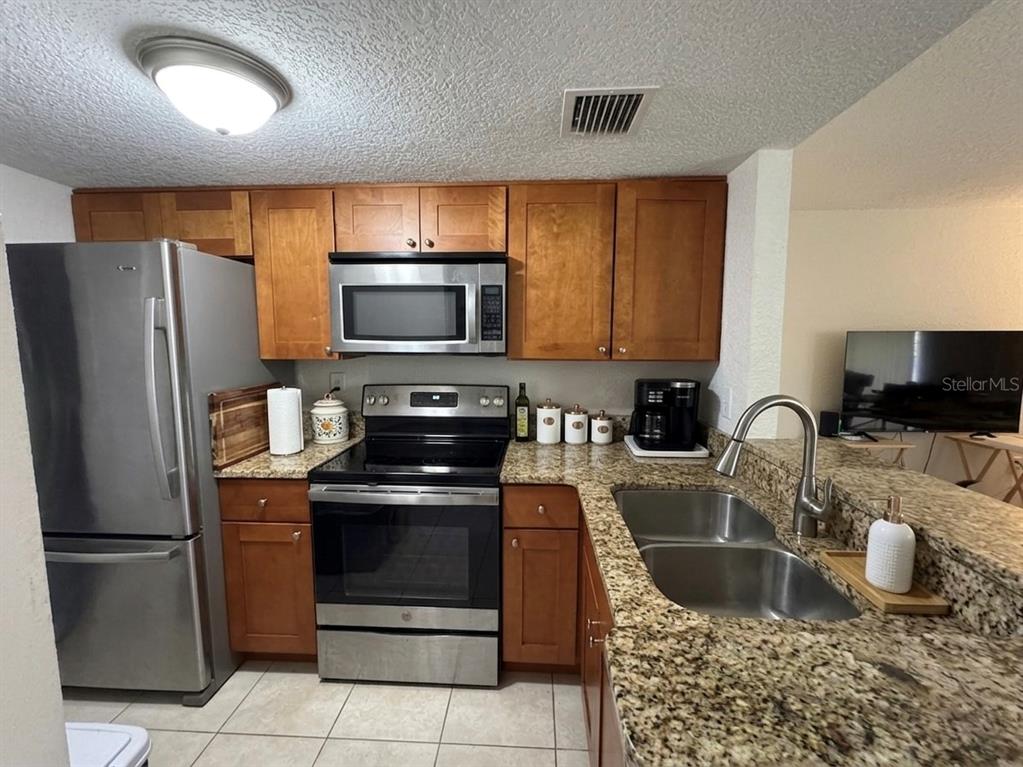 A kitchen features stainless steel appliances, wood cabinets, and granite countertops — 554 ORANGE DRIVE UNIT 15, ALTAMONTE SPRINGS, FL