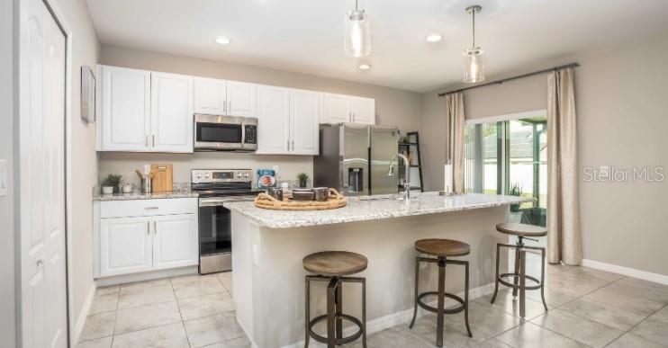 A kitchen with white cabinets, granite countertops, a center island, and three wooden bar stools — 16048 GALIANO COURT, PUNTA GORDA, FL