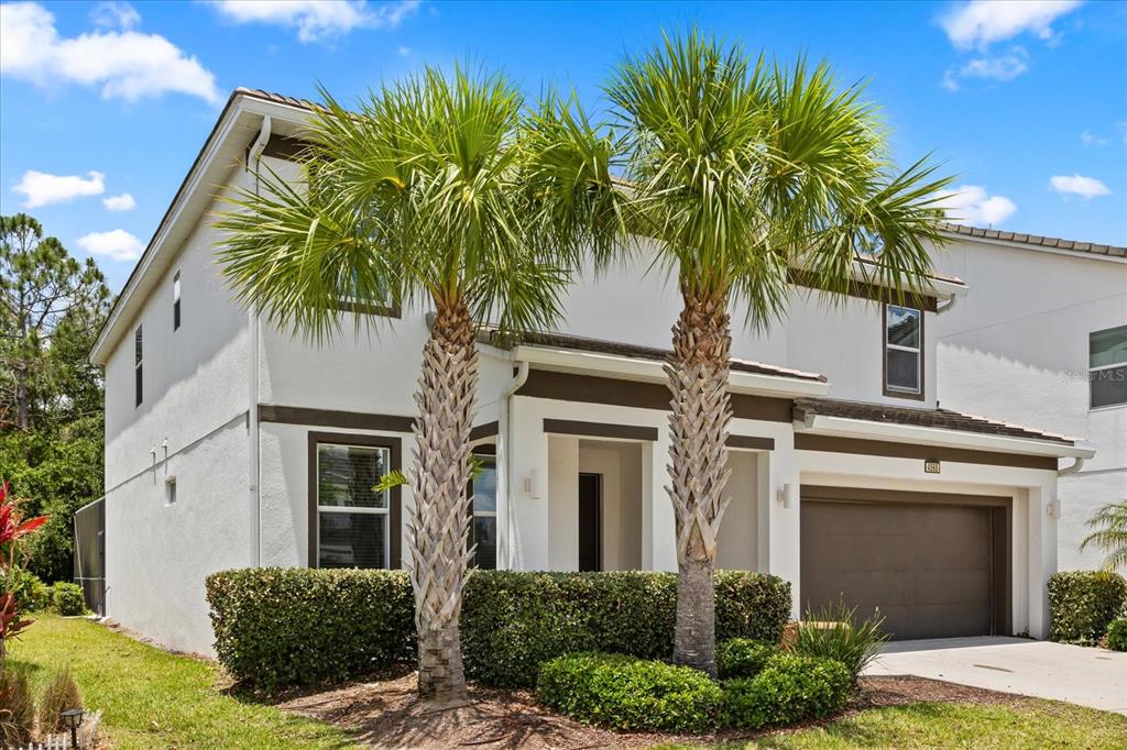 A two-story stucco house with a two-car garage and two palm trees in front — 4565 CABELLO LOOP, KISSIMMEE, FL