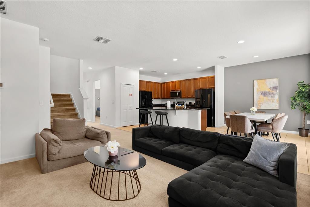 An open-concept living room features a black sectional sofa, a coffee table, and a kitchen — 4565 CABELLO LOOP, KISSIMMEE, FL