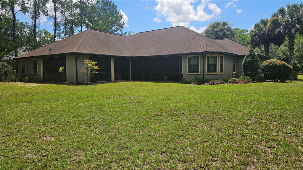 The back exterior of a single-story house features a large screened-in porch and grassy yard — 6019 NW 90TH STREET, GAINESVILLE, FL