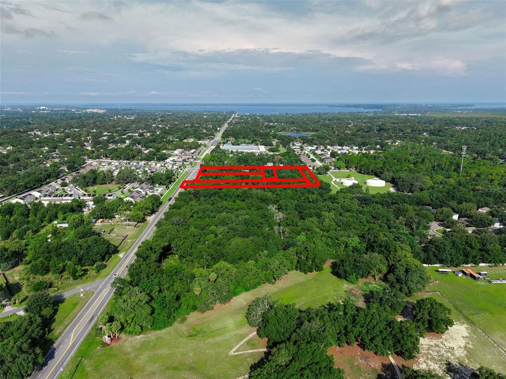 An aerial view shows a vacant, rectangular plot of land outlined in red near a road — E COUNTY ROAD 44, EUSTIS, FL