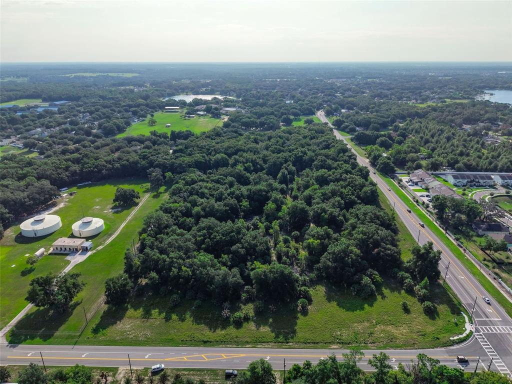 An aerial view shows a large wooded lot bordered by roads and nearby water tanks — E COUNTY ROAD 44, EUSTIS, FL