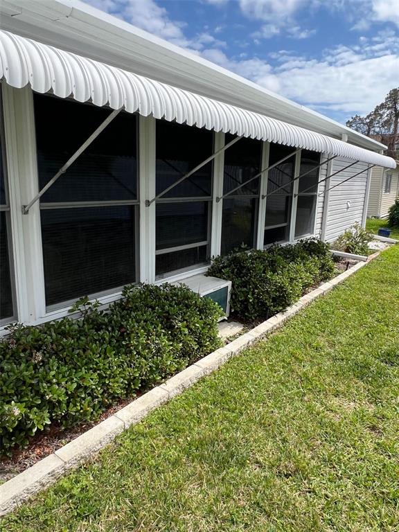 The exterior of a house features a white metal awning over windows and a small air conditioner — 709 SUGAR PALM STREET, LARGO, FL
