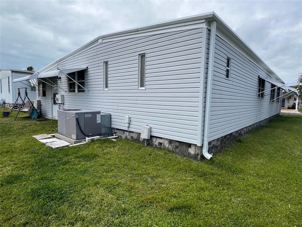 Exterior view of a light gray vinyl-sided mobile home with a central air conditioning unit — 709 SUGAR PALM STREET, LARGO, FL