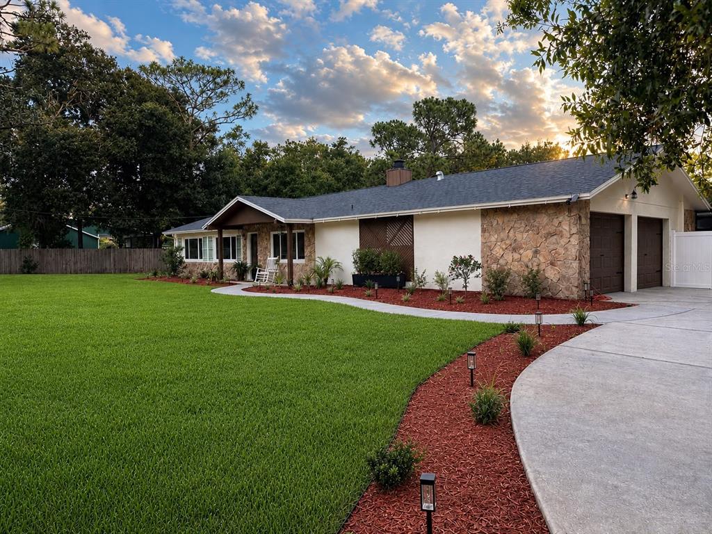 A single-story house with a stone facade, dark roof, and a curved walkway through red mulch — 17238 BRIDLEPATH COURT, LUTZ, FL