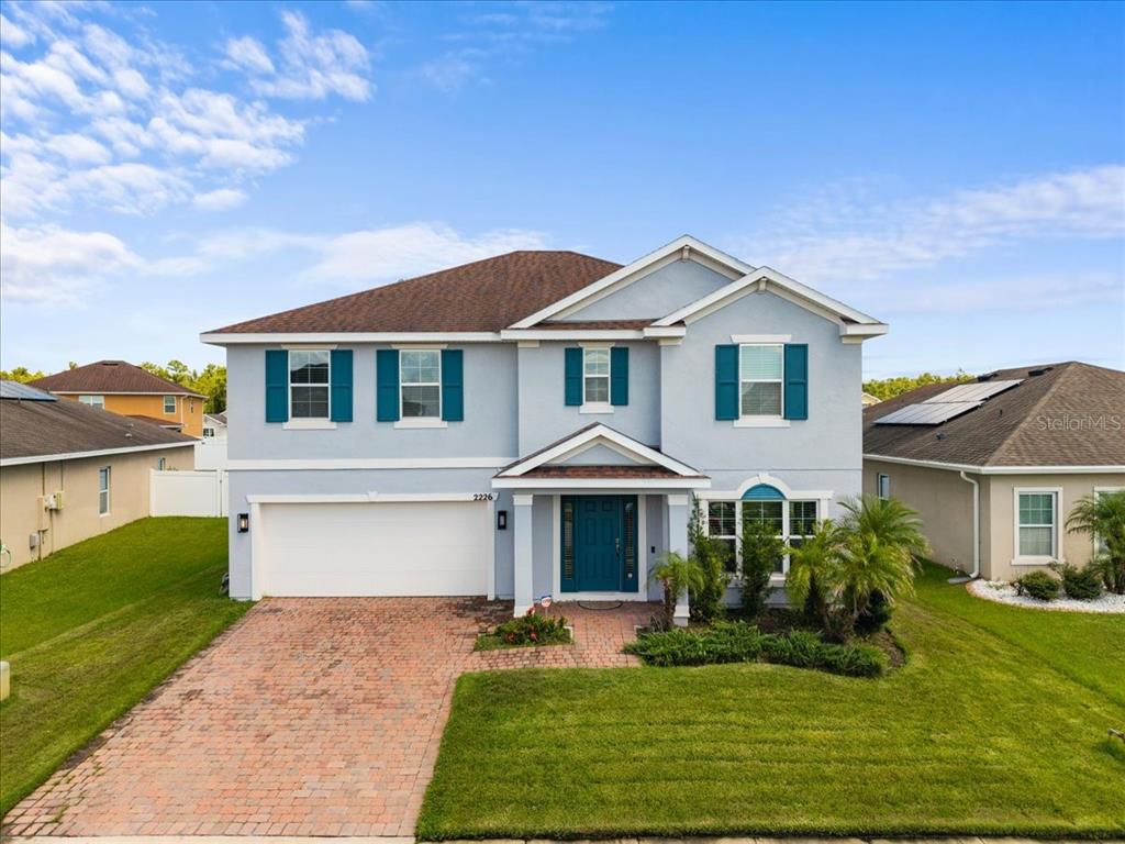 A two-story house with light blue siding, a brick driveway, and a two-car garage — 2226 TAYLOR CREEK COURT, KISSIMMEE, FL