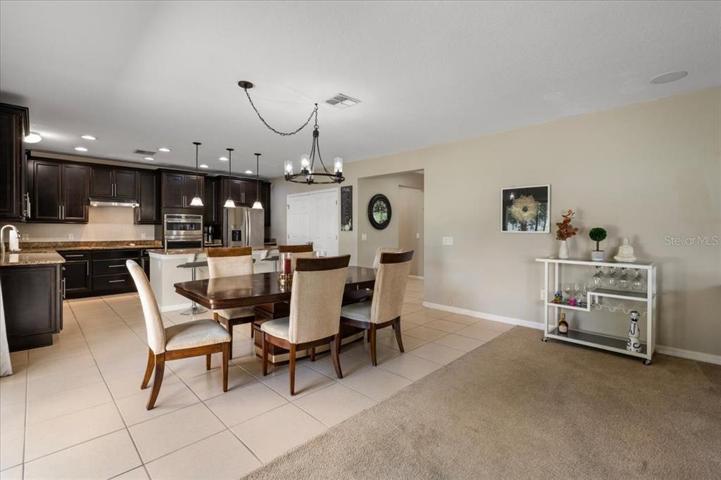 A dining area with a wooden table and chairs sits adjacent to a dark-cabinet kitchen — 2226 TAYLOR CREEK COURT, KISSIMMEE, FL