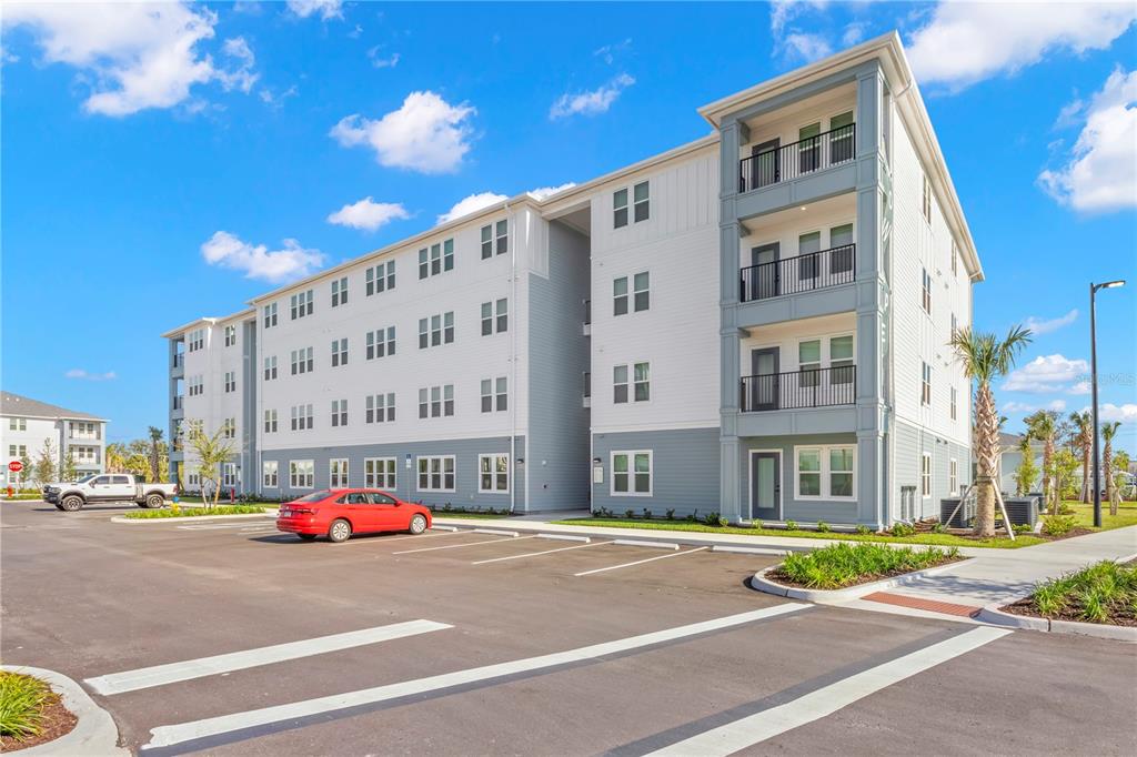 A multi-story apartment building with a parking lot and a red car in front — 9720 BEAMING ROAD UNIT B2, VENICE, FL