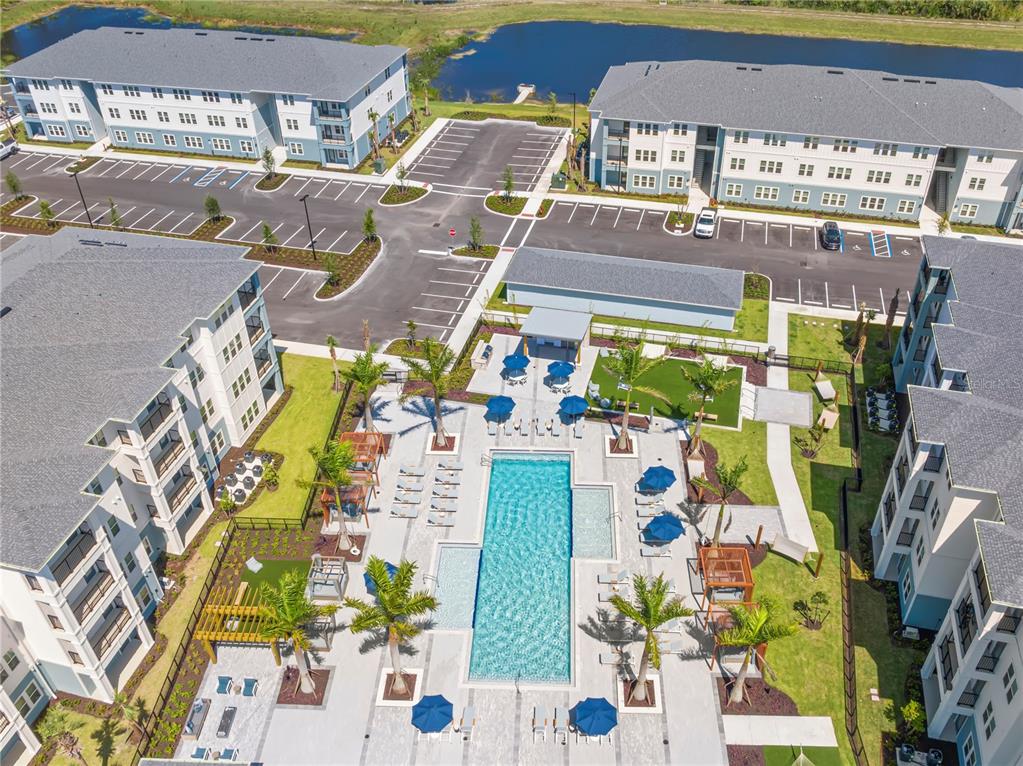 An aerial view shows a swimming pool area surrounded by apartment buildings and parking lots — 9720 BEAMING ROAD UNIT B2, VENICE, FL