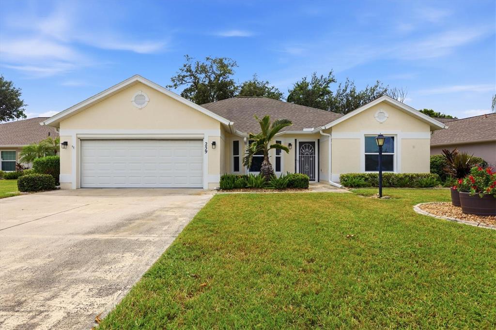 A single-story house with a two-car garage, beige stucco exterior, and a front lawn — 259 PARK FOREST BOULEVARD, ENGLEWOOD, FL