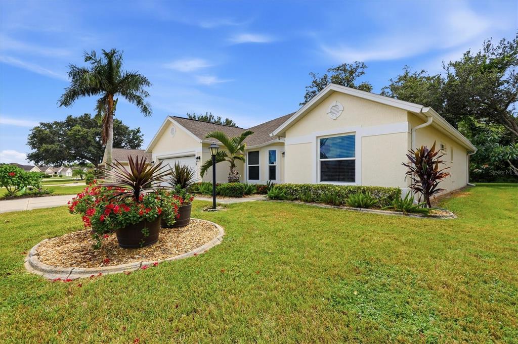 A concrete walkway leads to the front entrance of a light-colored house with landscaping — 259 PARK FOREST BOULEVARD, ENGLEWOOD, FL