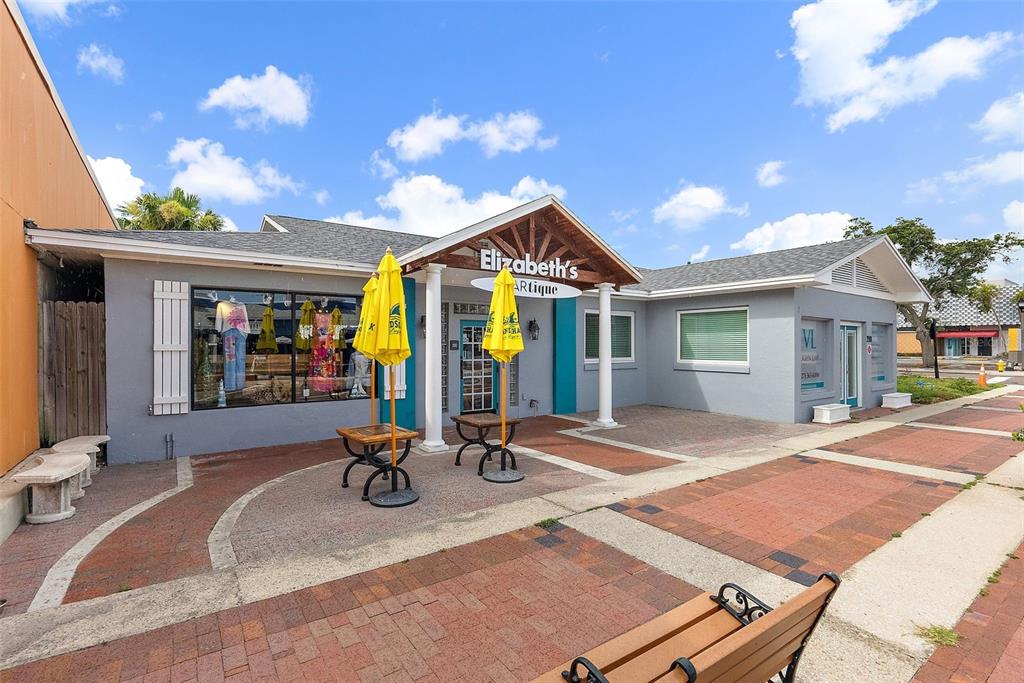 The exterior of a gray commercial building features a front entrance with yellow umbrellas — 350 COREY AVENUE, ST PETE BEACH, FL