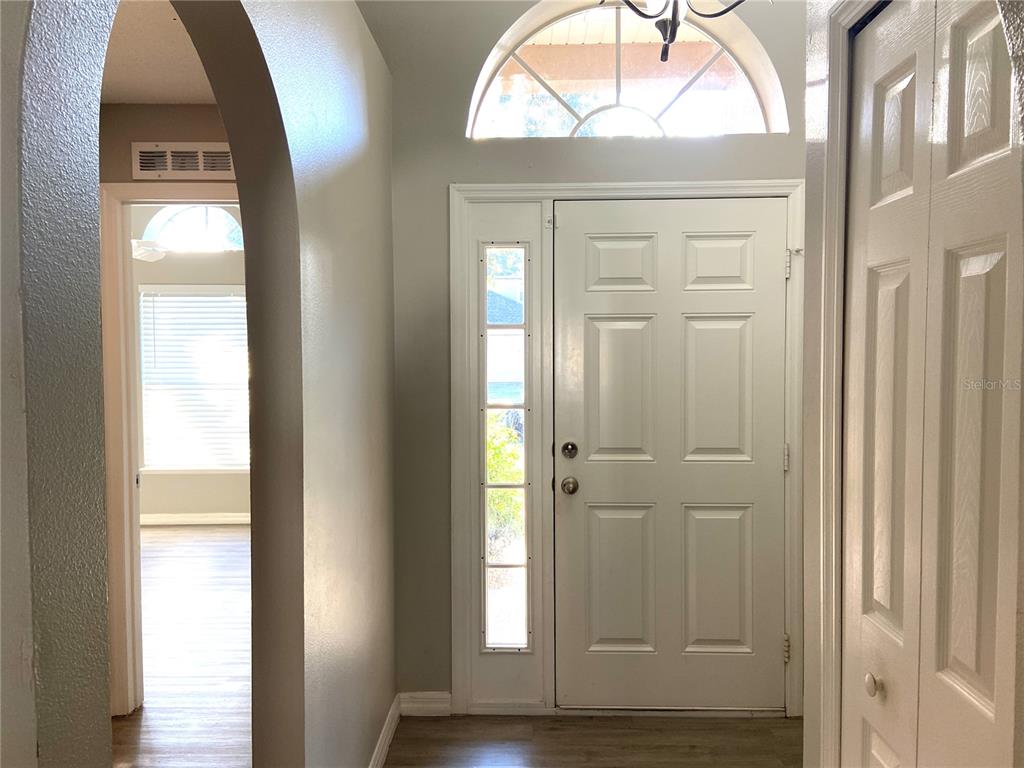 An entryway features a white front door with a sidelight, an arched opening, and light flooring — 10459 FLY FISHING STREET, RIVERVIEW, FL