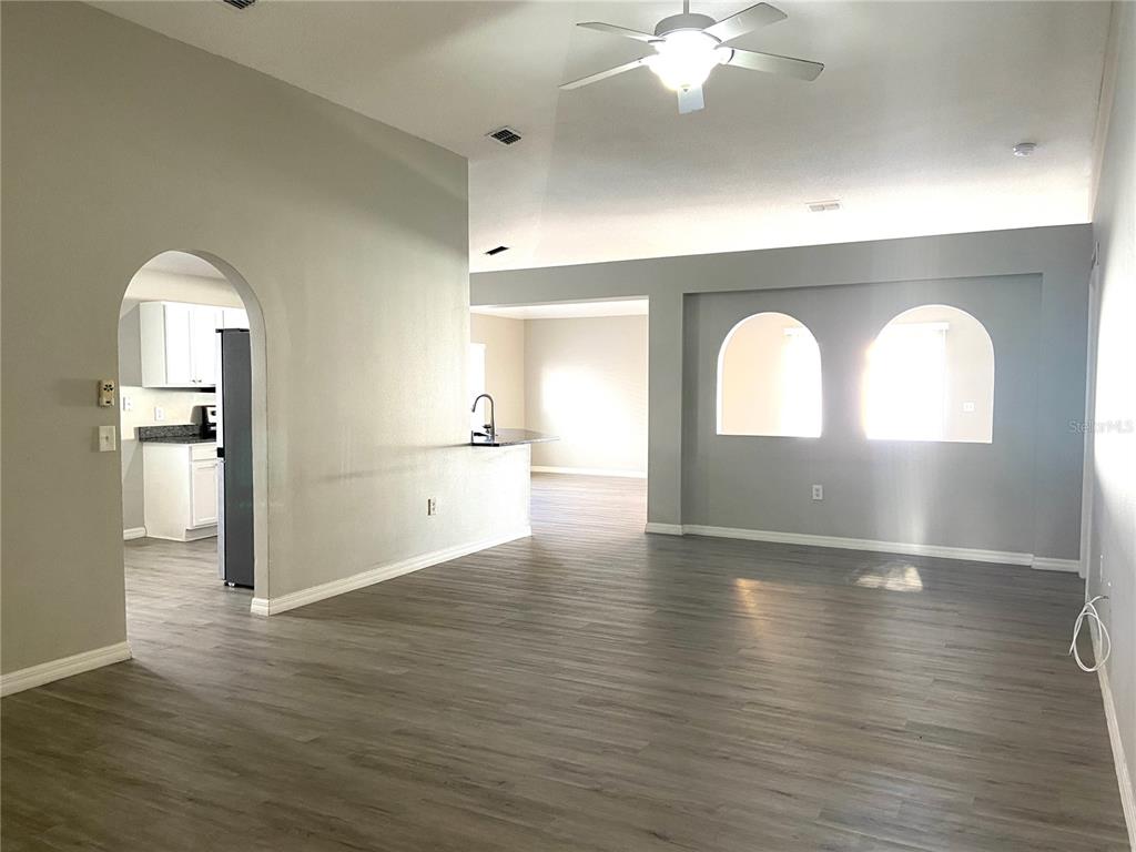 An open-concept living area features gray walls, wood-look flooring, and two arched wall cutouts — 10459 FLY FISHING STREET, RIVERVIEW, FL