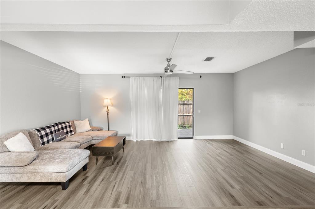 A living room features light gray walls, wood-look flooring, a sectional sofa, and a sliding door — 707 SAINT MATTHEW CIRCLE, ALTAMONTE SPRINGS, FL