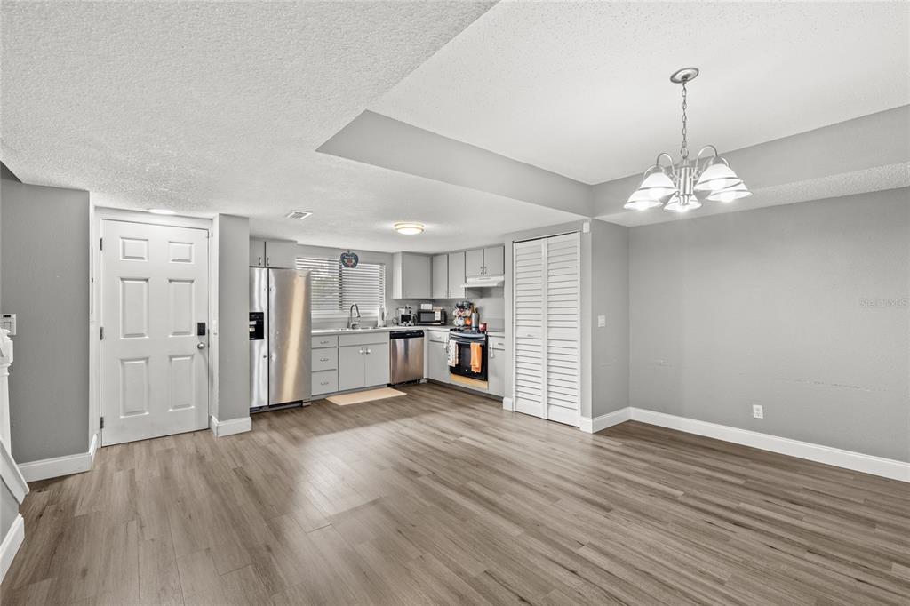 A kitchen and dining area with gray walls, wood-look flooring, and white cabinetry — 707 SAINT MATTHEW CIRCLE, ALTAMONTE SPRINGS, FL
