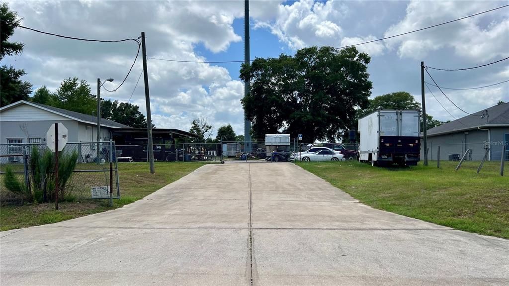 A concrete driveway leads to a fenced storage lot with a truck and parked vehicles — 460 NW 68TH AVENUE, OCALA, FL
