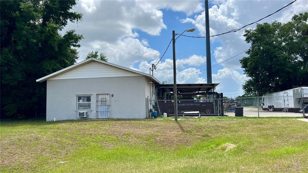 A single-story building with a gray exterior, a metal carport, and a chain-link fence — 460 NW 68TH AVENUE, OCALA, FL