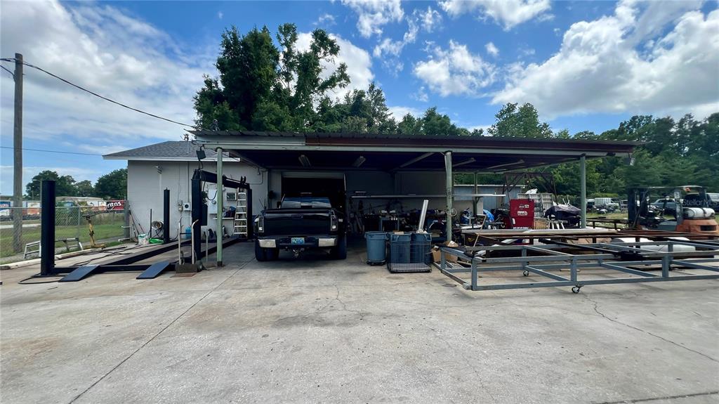 A black pickup truck is parked under a large metal carport attached to a building — 460 NW 68TH AVENUE, OCALA, FL