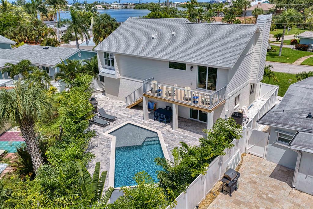An elevated rear view of a two-story house featuring a deck, pool, and patio area — 503 JANICE PLACE, INDIAN ROCKS BEACH, FL