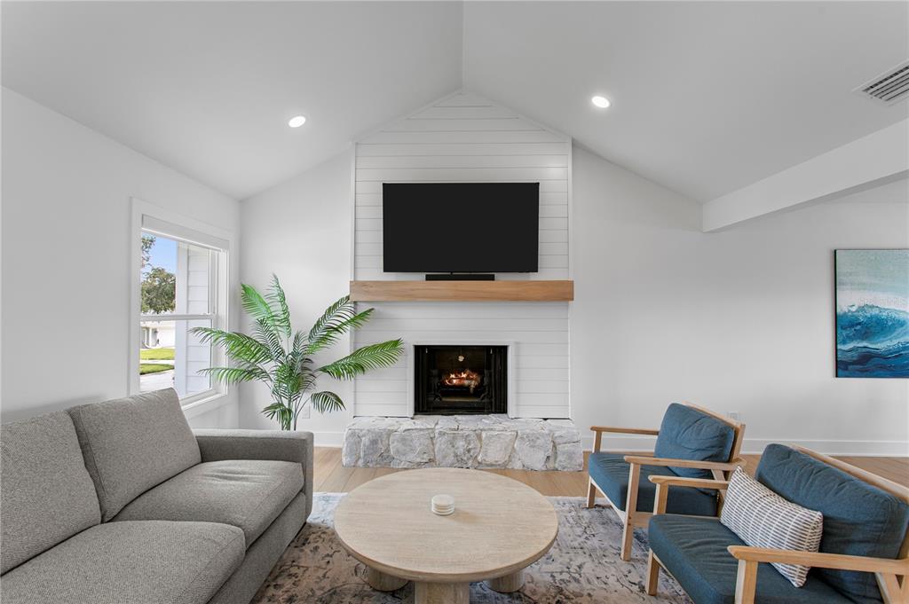 A living room features a stone fireplace, shiplap wall, vaulted ceiling, and modern furniture — 503 JANICE PLACE, INDIAN ROCKS BEACH, FL