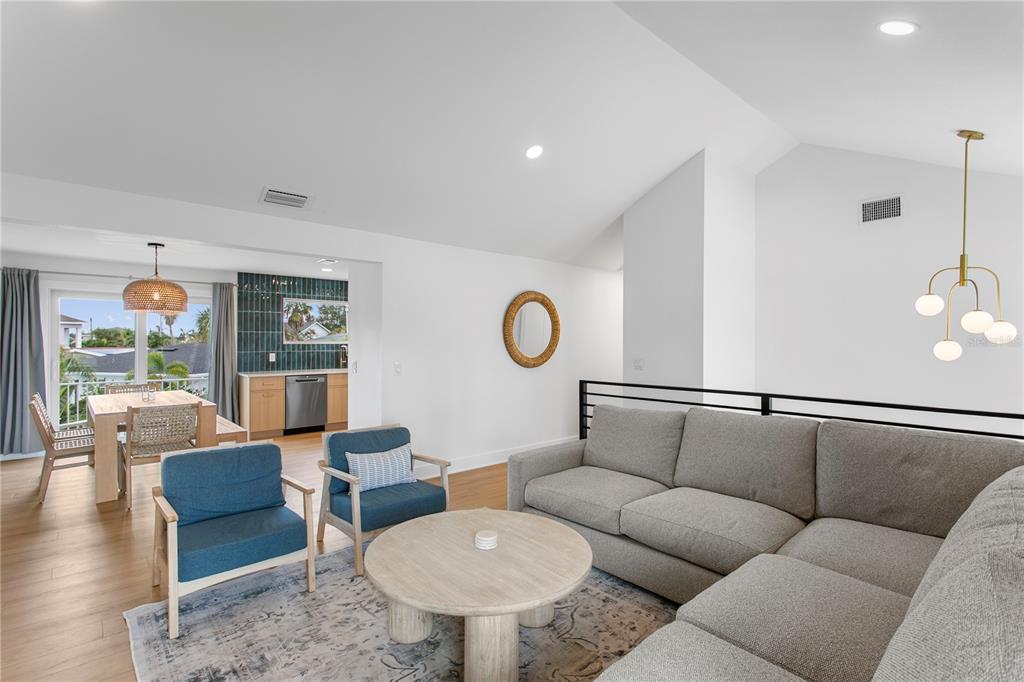 A living room with a gray sectional, two blue chairs, and an adjacent dining area — 503 JANICE PLACE, INDIAN ROCKS BEACH, FL