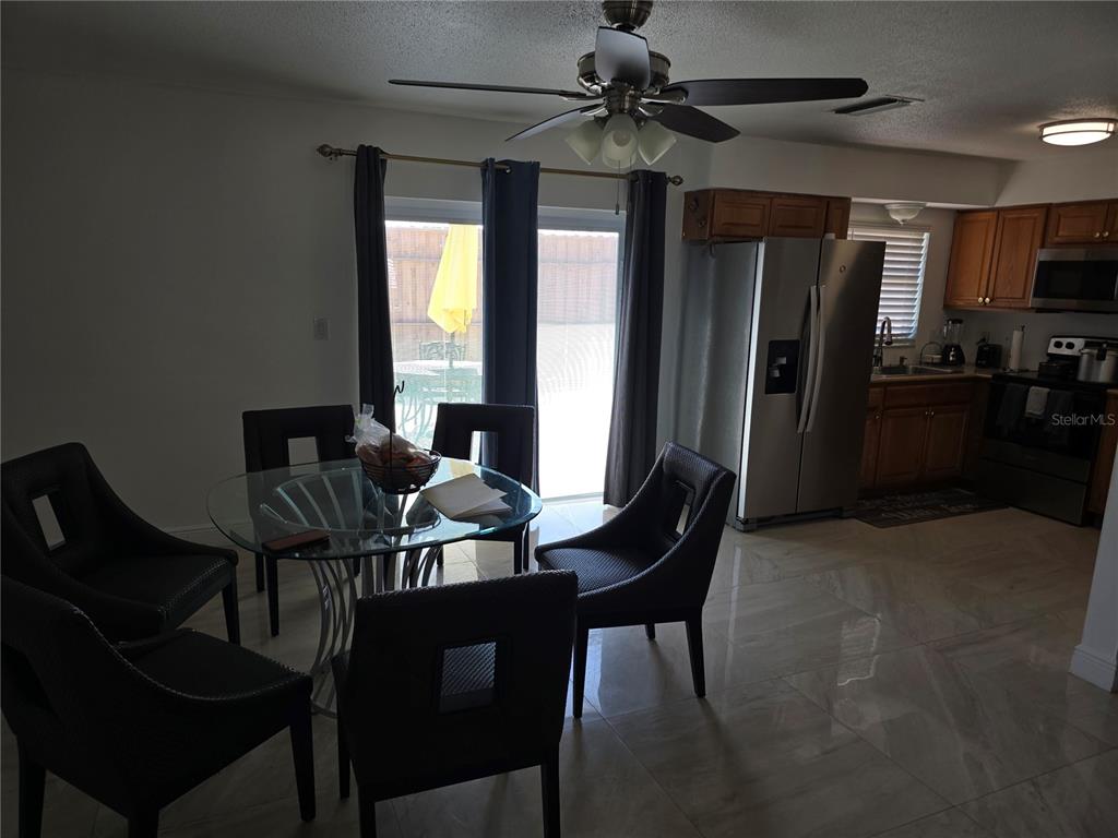 A dining area with a glass table and chairs sits adjacent to a modern kitchen — 537 MELODY CIRCLE, SARASOTA, FL