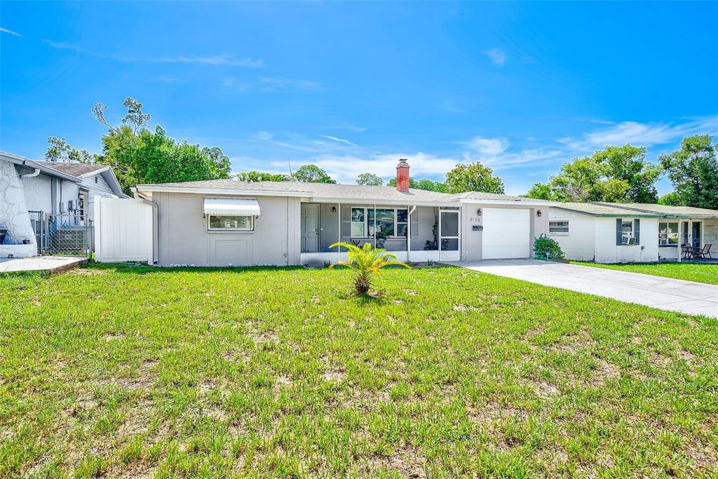 A single-story house with a gray exterior, a brick chimney, and a front lawn — 5126 ROSEWOOD DRIVE, NEW PORT RICHEY, FL