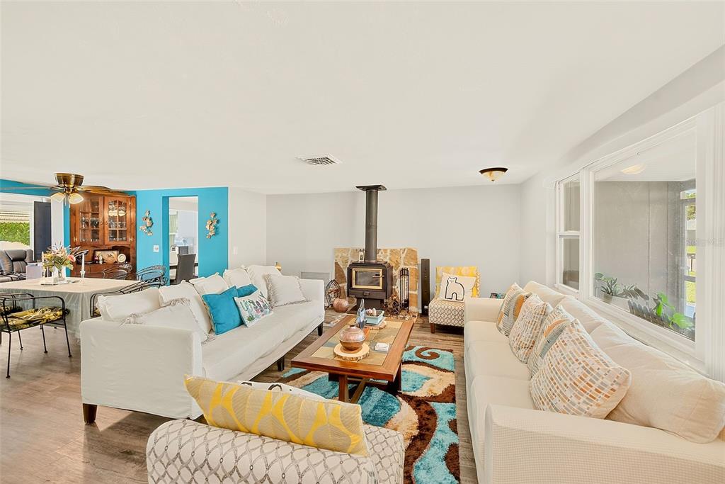 A living room features two white sofas, a wood-burning stove, and a colorful area rug — 5126 ROSEWOOD DRIVE, NEW PORT RICHEY, FL